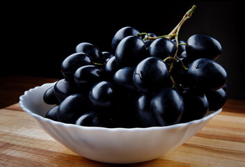 Large ripe black grapes in a white plate.