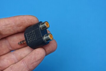 one small black adapter lies on the fingers on the hand on a blue background