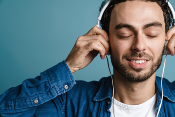 Pleased handsome guy listening music with headphones