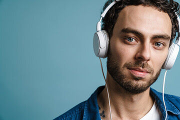 Unshaven handsome guy listening music with headphones