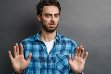 Unshaven tense guy showing stop gesture on camera
