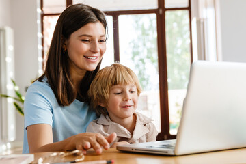 Woman at home with her son using laptop computer