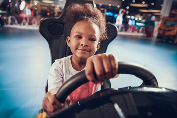 Girl holding wheel while playing virtual racing. 