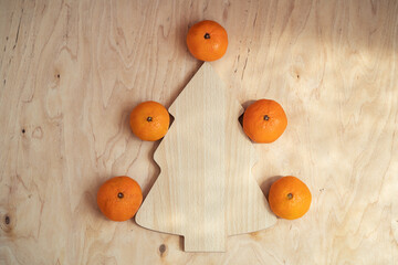 Tangerines around a cutting board in the form of a herringbone on a wooden table. Top view and copy space. Merry Christmas and happy new year concept.