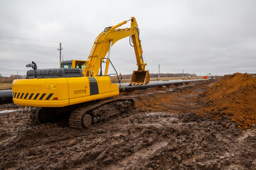 Obraz premium laying the pipeline with an excavator. Autumn, shooting from a drone. Earthworks, infrastructure construction