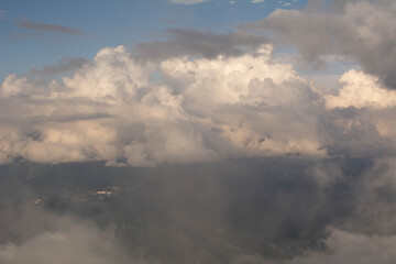 Fototapeta premium view from the top of the mountain through the clouds to the valley in the sun