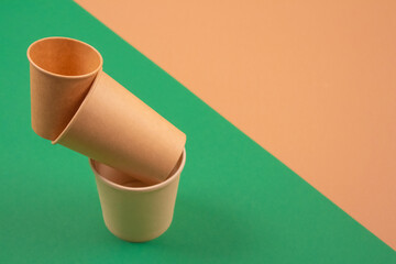 Set of balancing bioderadable takeaway beverages cups - kraft paper coffee cups on green and brown background with copyspace. Recycled kraft paper tableware and zero waste concept, mockup image