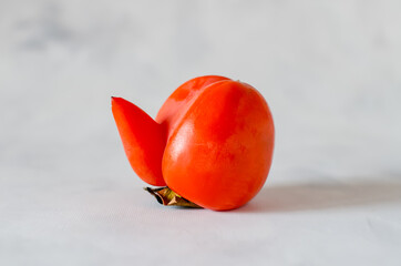 A strange shape of fruit. Ugly persimmon on a gray background. Sweet tasty kaki fruit. The concept...