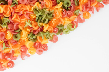 Multicolored pasta scattered on a white background. Top view. Copy, empty space for text