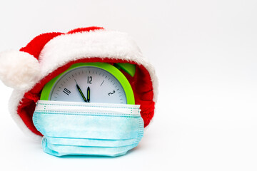 New Year alarm clock santa hat medical mask on white background countdown to midnight.Copy space.