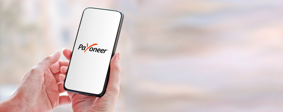 Chelyabinsk, Russia - March 25, 2020. Smartphone in hand with the Payoneer logo - a payment system that provides financial services and online money transfers.