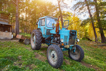 An old blue tractor stands in a farmyard