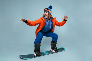 Handsome excited sportsman riding on a snowboard