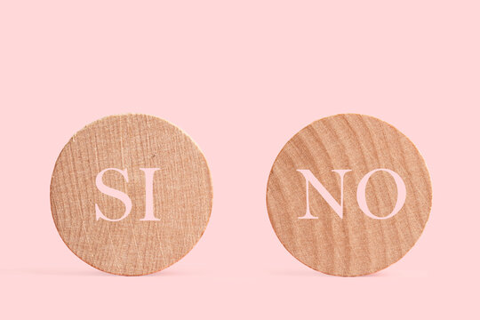 Dos círculos de madera con palabras escrita Si y No sobre un fondo rosa liso y aislado. Vista de frente. Copy space