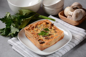 Homemade quiche or pie with  broccoli, seasonings, champignons and cheese on a gray background.