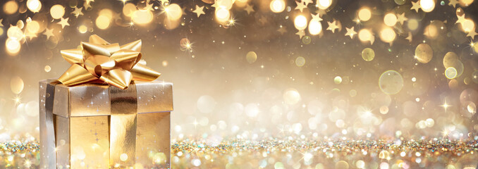 Golden Gift Box On Glitter In Abstract Background With Defocused Lights