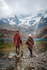 A young couple with ponchos on vacation in Laguna Humantay, Peru
