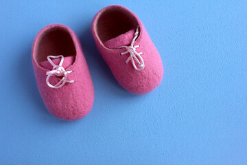 Felted woolen pink booties for a newborn on a blue background