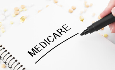Doctor writes word MEDICARE on a white notepad