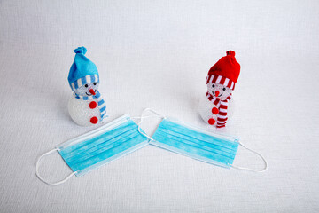 decorative snowmen and a medical mask on a white background, there is a place for text, the concept of meeting the new year against the background of the coronavirus epidemic. Save your life, be quara