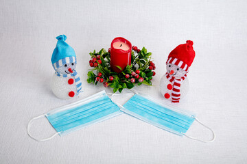 Decorative snowmen for the new year, candles, fir branch, medical mask. Concept, Christmas in the coronavirus epidemic, congratulate friends, but stay in corantin