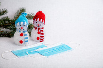 Fir tree branch, decorative snowmen and a medical mask on a white background, there is a place for text, the concept of meeting the new year against the background of the coronavirus epidemic. Save yo