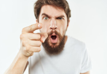 Emotional man gesticulates with his hands on a light background and a thick beard irritability