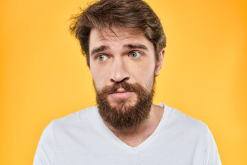 Obraz premium Man with emotional expression white t-shirt close-up studio yellow background