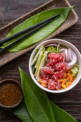 Healthy organic raw tuna poke bowl with cucumber, rice, carrots, onion served in bowl on wooden table. Healthy lifestyle