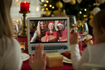 A happy family with a child is celebrating Christmas with their friends on video call using webcam....
