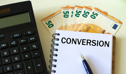 CONVERSION word in a notebook against the background of calculitar and banknotes