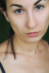 close-up of a young brunette woman looking at the camera on a green background