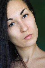 close-up of a young brunette woman looking at the camera on a green background