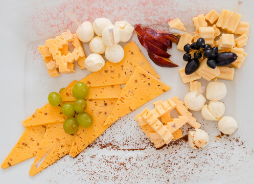 Cheese Plate: Cheddar, Gouda, Mozzarella And Others With Grapes On A White Board. View From Above.