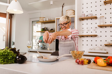 Happy senior woman cooking in her modern kitchen
