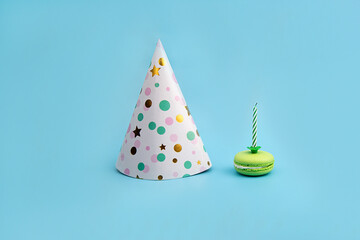 Colorful Hat for Party and green Macaroon with a candle on a blue background. Creative concept of a holiday, birthday.