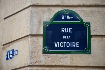 Closeup of Victory street name on the traditional parisian street plate on stoned building - (rue de la victoire in french) - obrazy, fototapety, plakaty