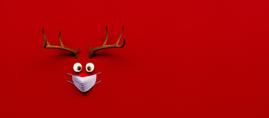 Rentierspielzeug mit kalter roter Nase und medizinischer Maske auf rotem Weihnachts-Corona-Hintergrund 3D-Rendering