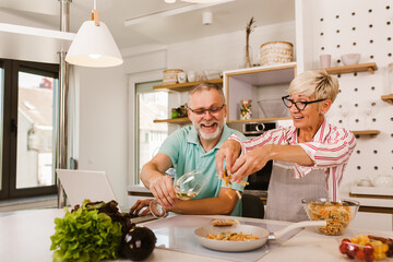 Senior couple preparing food in the kitchen, having fun.