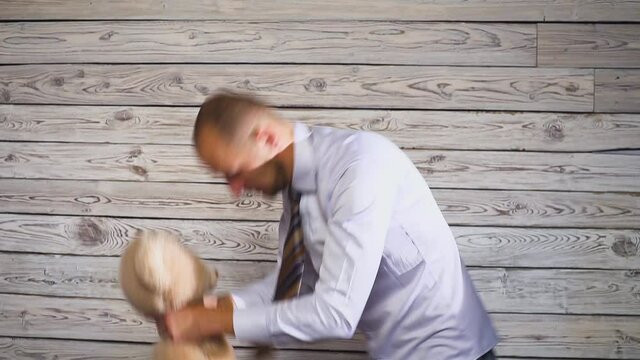 Young angry businessman beating a stuffed bear toy in his office. Concert on the theme of frustration