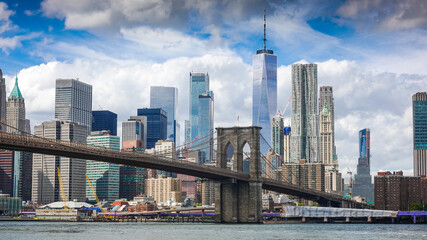View from Brooklyn Bridge to Manhattan in New York during sunny day with blue sky and white clouds