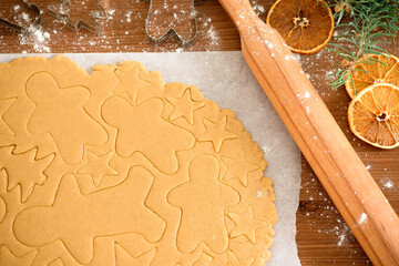 cut gingerbread out of the dough using a gingerbread mold, top view, raw dough with cinnamon prepared for baking . the pattern on the dough of the figures