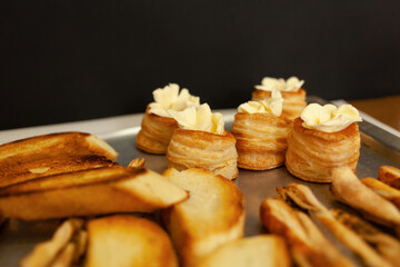 Baskets of puff pastry with butter and pate. Baking on a tray, black