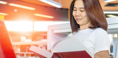 University students reading book in library. Asia collage woman and man study research with smartphone in school campus. Academic education background with copyspace concept.