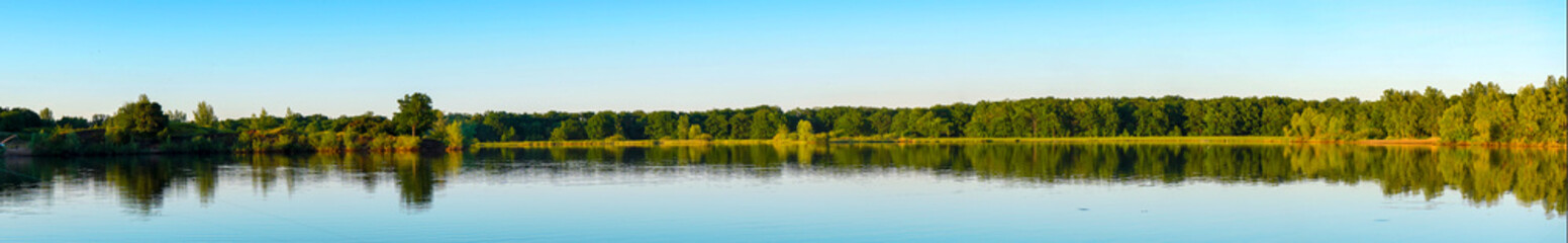 Fototapeta na wymiar Panorama of the lake with a forest on the opposite shore