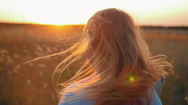 Young girl with her back in the field and look sunset.