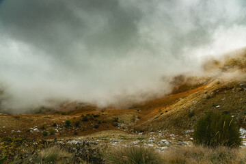 Scenic landscape view with mountain slope in low lying cloud
