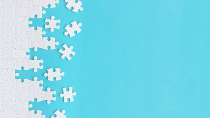 Assembling jigsaw puzzle pieces, Top view unfinished white jigsaw puzzle on blue background, Fragment of a folded white jigsaw puzzle with copy space, Teamwork and problem solving concept.