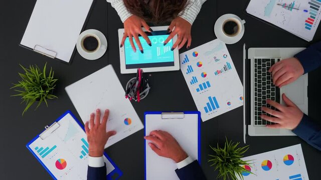 Top view of business people having meeting analysing financial statistics graphs planning next project using digital devices on corporate office. Teamwork brainstorming on copy space, flat lay concept