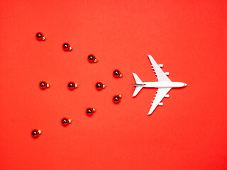 Airplane and ornaments on red paper background. Christmas or New Year festive concept. Flat lay, top view.